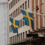 Two Sweden flags mounted on the front of a brick building.