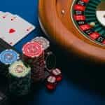 Poker chips, playing cards, and a roulette wheel placed on a table next to a keyboard.