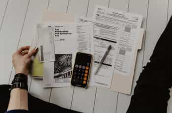 Documents and calculator on phone kept on wooden floor.