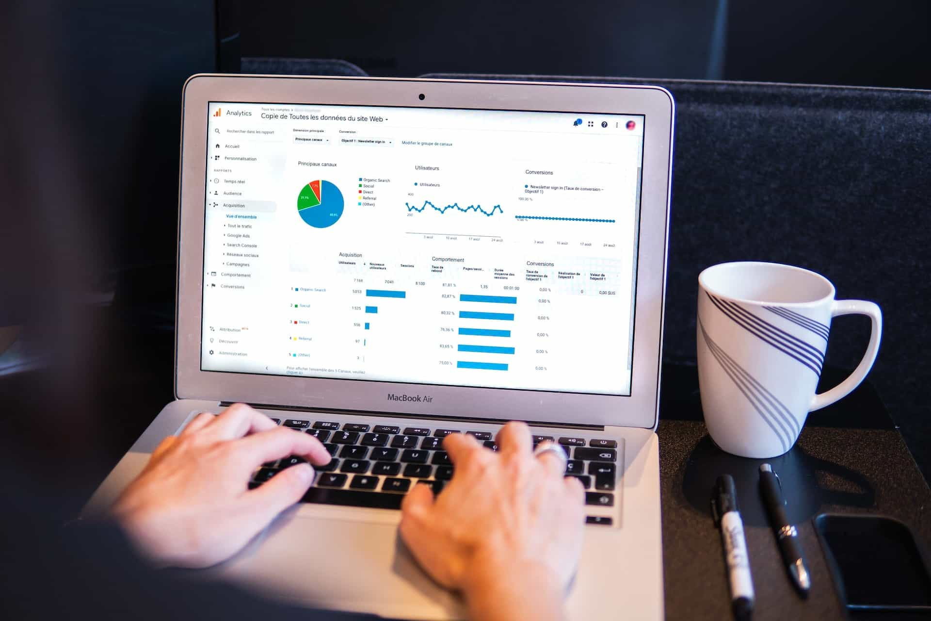 A person typing on a Macbook with analytics on the screen.