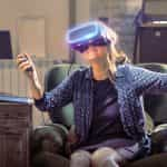 A smiling woman trying a virtual reality headset.